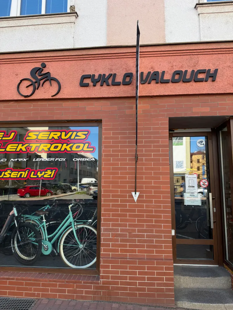 Vchod do prodejny pod nápisem Cyklo Valouch, vlevo výloha s nápisy Servis a Elektrokol